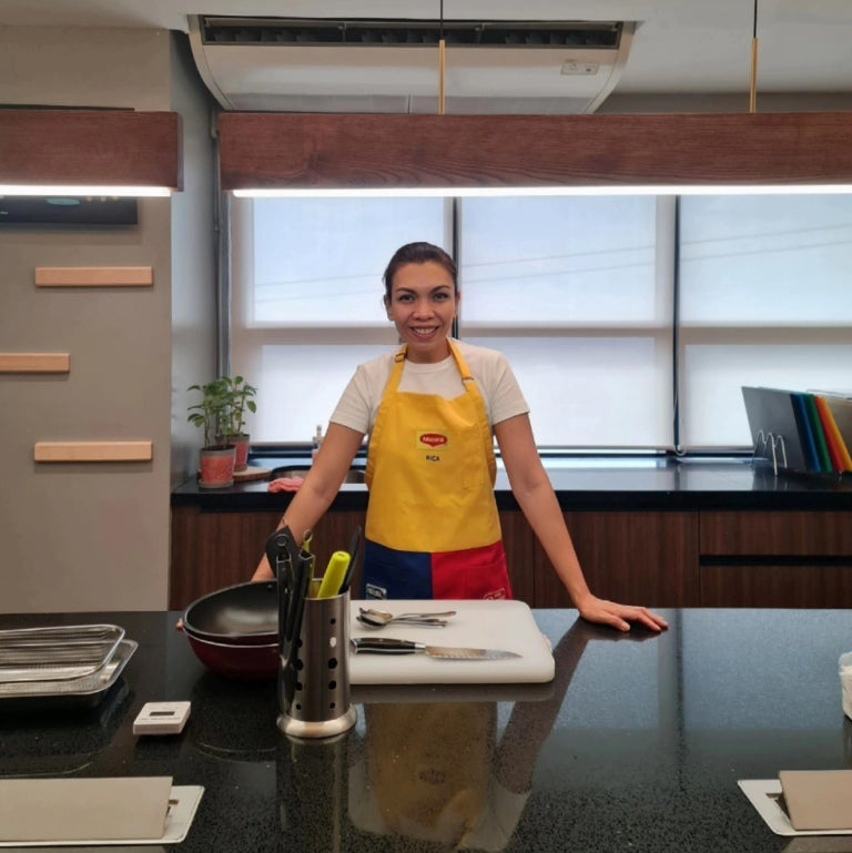 A person in a yellow "Maggi" apron stands at a modern kitchen counter.